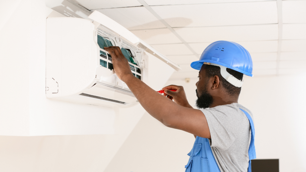 An HVAC technician adjusts a component on an AC unit.