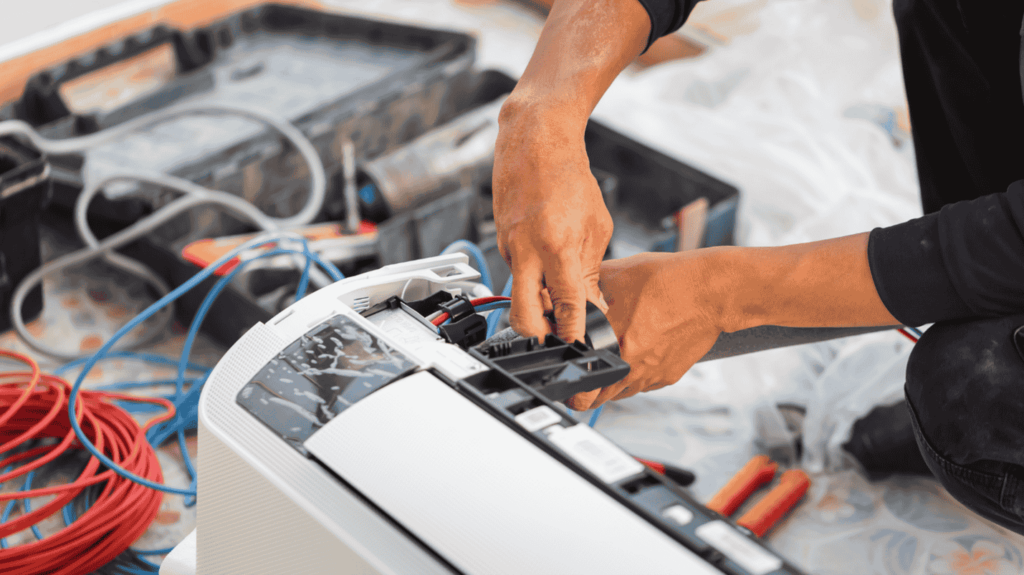 An AC unit sits among various cords during an AC replacement.